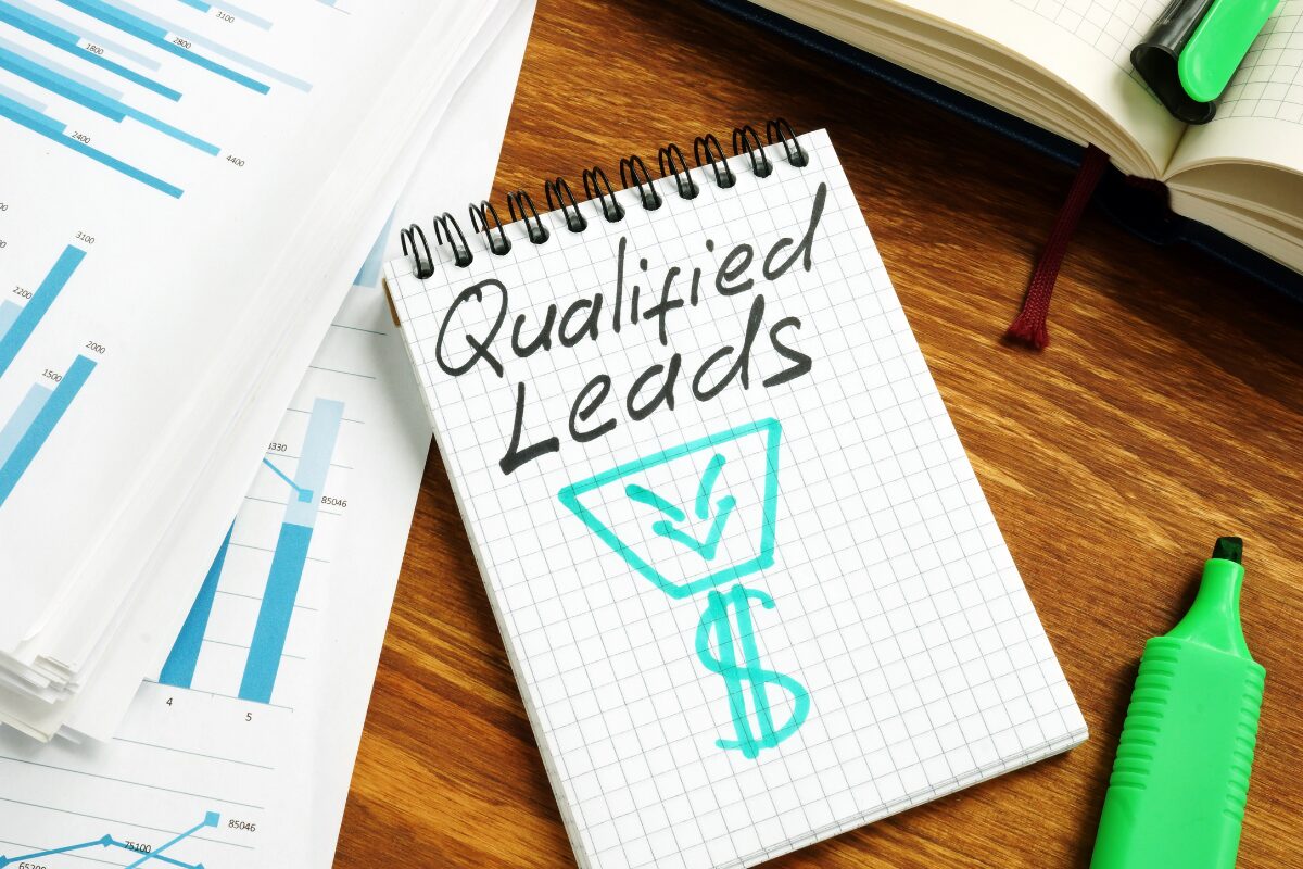 Writing on tablet that says "qualified leads" along with a funnel and dollar sign+